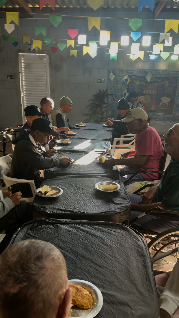 Grupo de idosos almoçando juntos sob bandeirinhas coloridas
