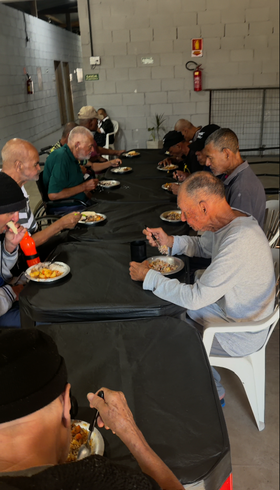 Idosos sentados à mesa compartilhando o almoço